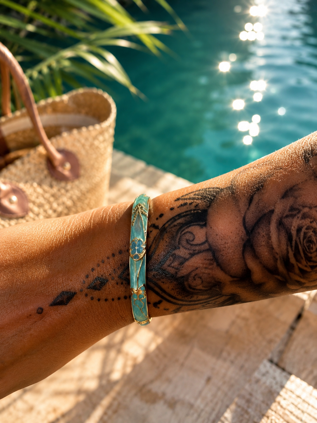 Bracelet jonc Éclat Tendance coloris Turquoise — émail turquoise et fleur dorée, porté au poignet au bord de la piscine